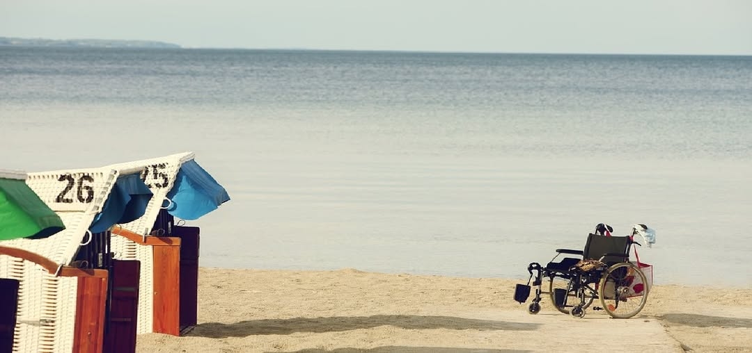 Εικόνα με αμαξίδιο στην παραλία κοντά στη θάλασσα.