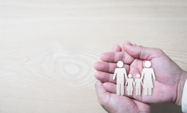 Εικόνα με δύο χούφτες ου προστατεύουν μια οικογένεια.