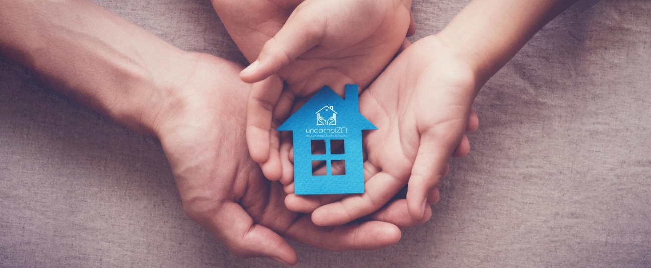 Λογότυπο της ΣΥΔ Υποστηρίζω στην Καρδίτσα με γραφικό χούφτες χεριών, που κρατούν ένα σπίτι.