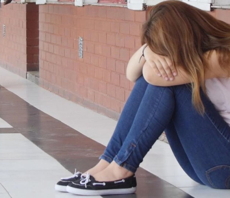Εικόνα μαθήτριας που κάθεται στο πάτωμα με σκυμένο το πρόσωπο, μετά από κάποιο δυσάρεστο γεγονός.