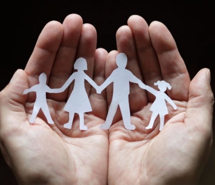 Εικόνα που δείχνει δύο παλάμες που κρατούν τα μέλη μίας οικογένειας που απεικονίζονται με χαρτί.