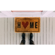 Εικόνα που δείχνει ένα χαλάκι που γράφει home και συνοδεύει την ανάρτηση του Ερμή για την πρόσκληση για την Στέγη.